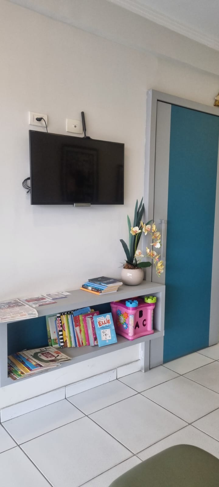 Cantinho infantil da sala de espera, com livros, brinquedos e televisão para crianças